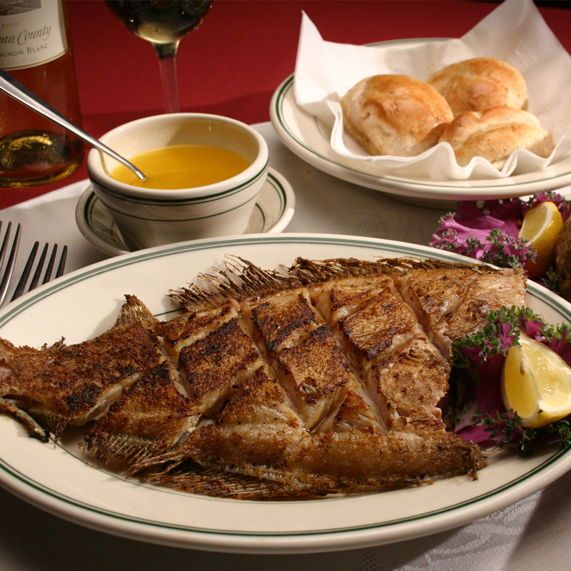 image of a grilled flounder with melted butter and rolls on a table